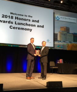 Joshua Fu accepts the Lyman A. Ripperton Environmental Educator Award on a stage.