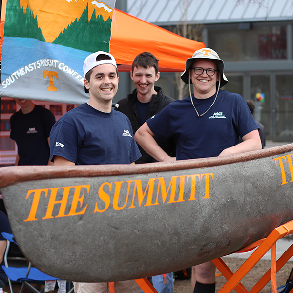 Three UT students stand behind their concrete canoe.