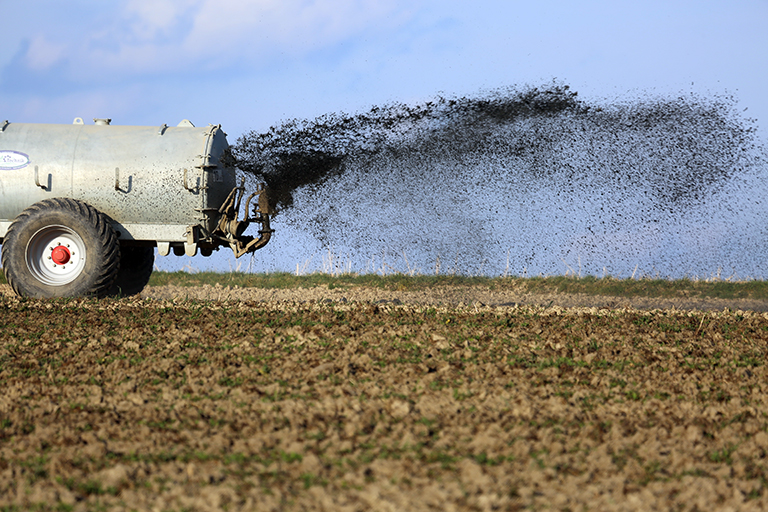 A truck sprays fertilizer over a field.