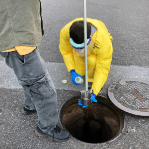 Student collects sample from wastewater for COVID-19 testing.