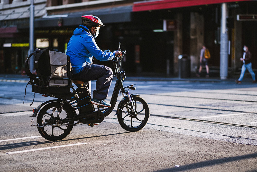 Person riding an e-bike is stopped at an urban intersection.