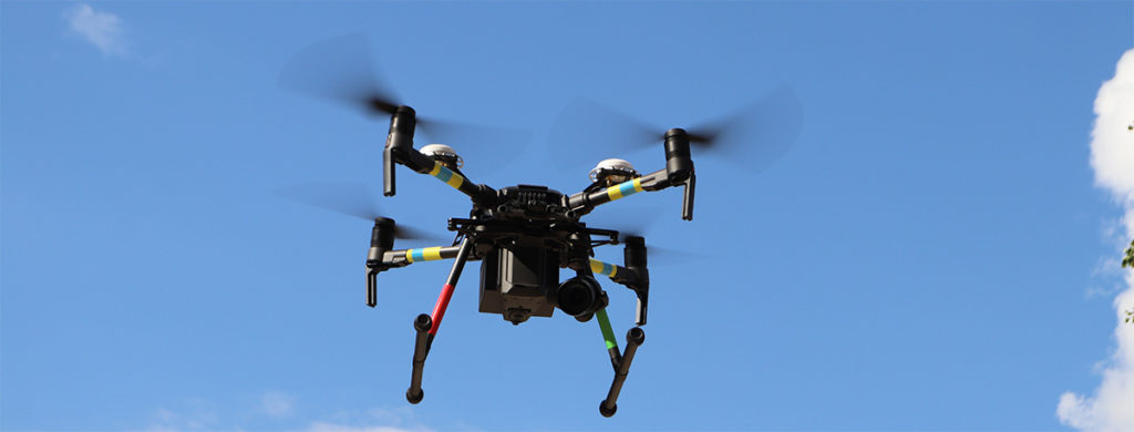 A drone used for inspection services by graduate students in flight with a blue sky background.