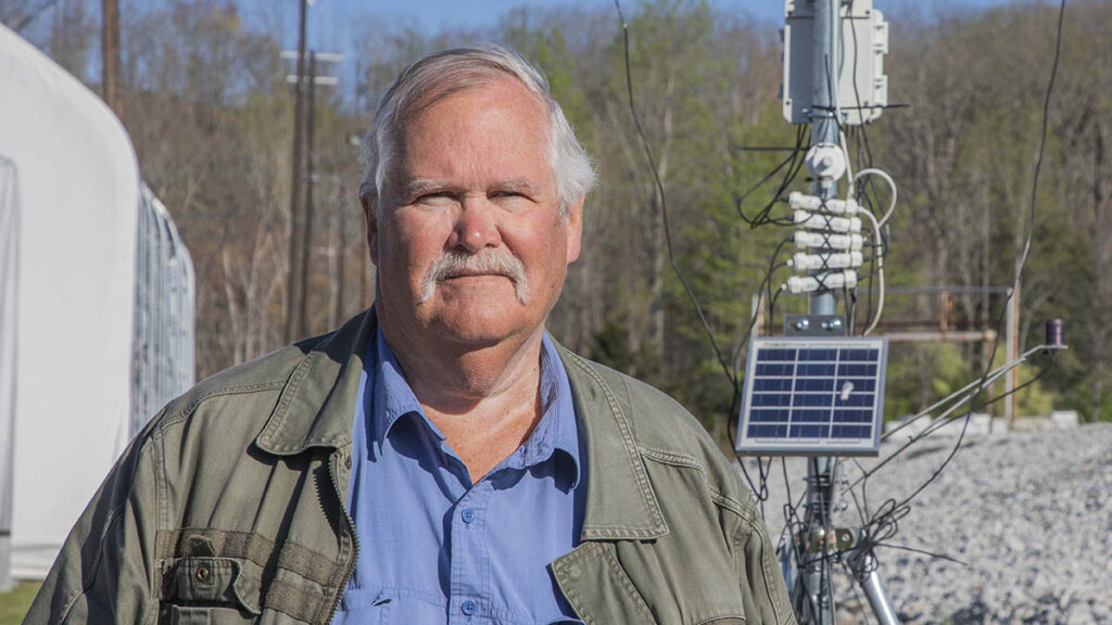 Terry Hazen stands next to a weather station.