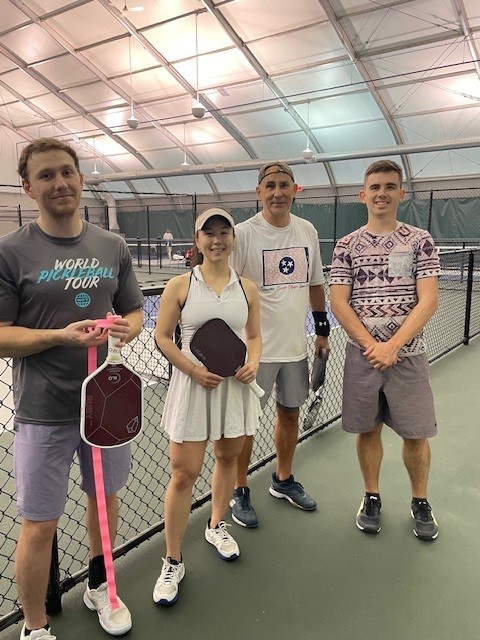 Trent Walker, Elina Geut, Chris Tabeling, and Colby Childress standing on a pickleball court