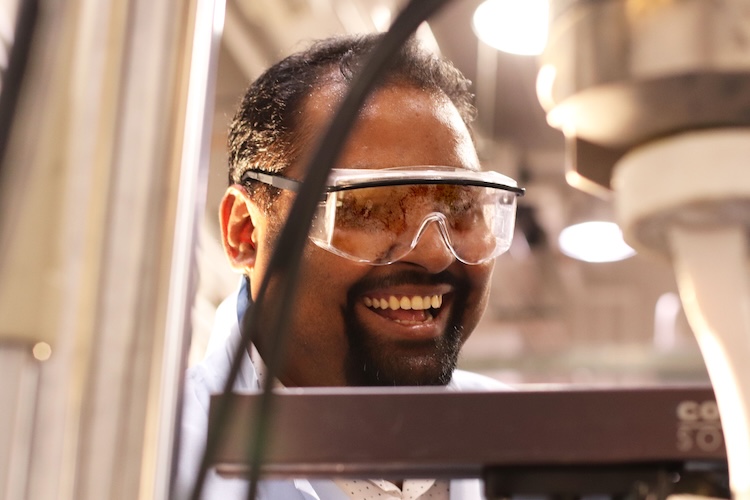Debangshu Paul working in a lab wearing a coat and safety glasses