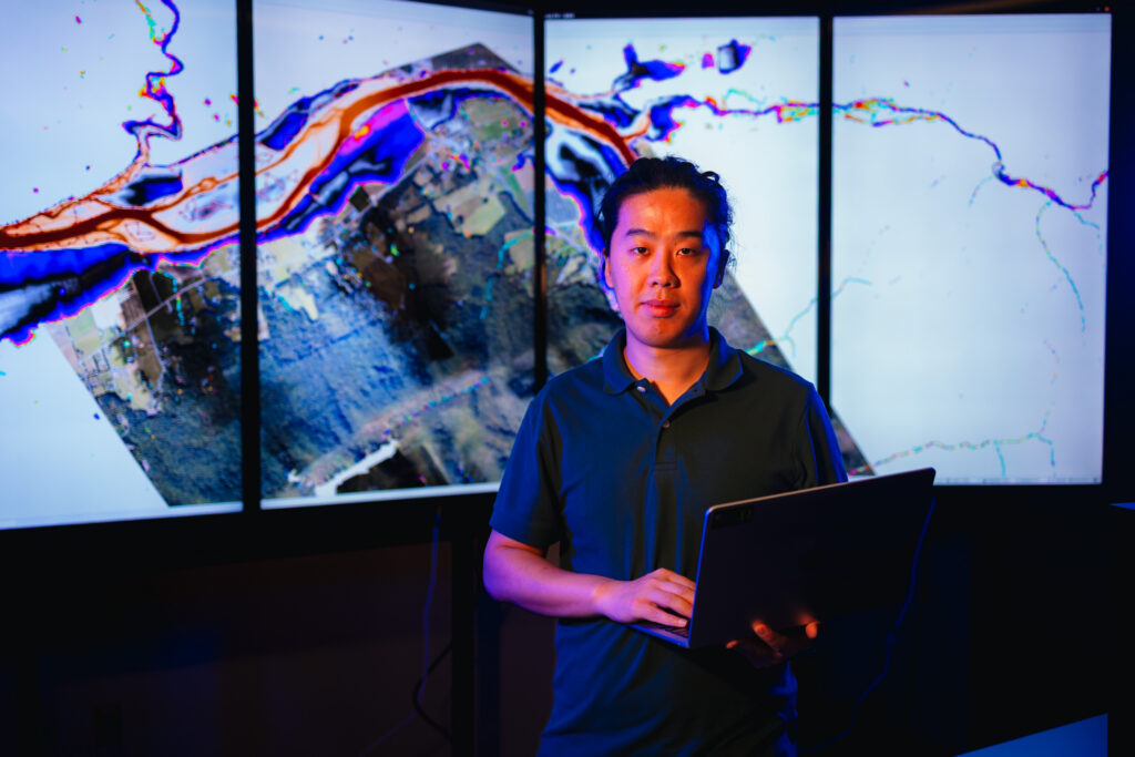 Assistant Professor Haochen Li standing in front of a flood risk map of Tennessee